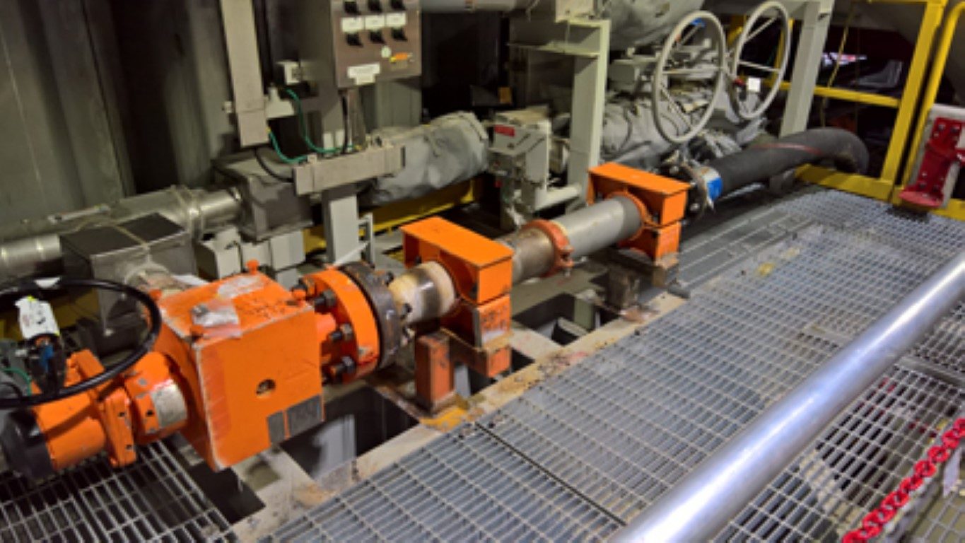 Orange pump components and connected piping inside an industrial facility